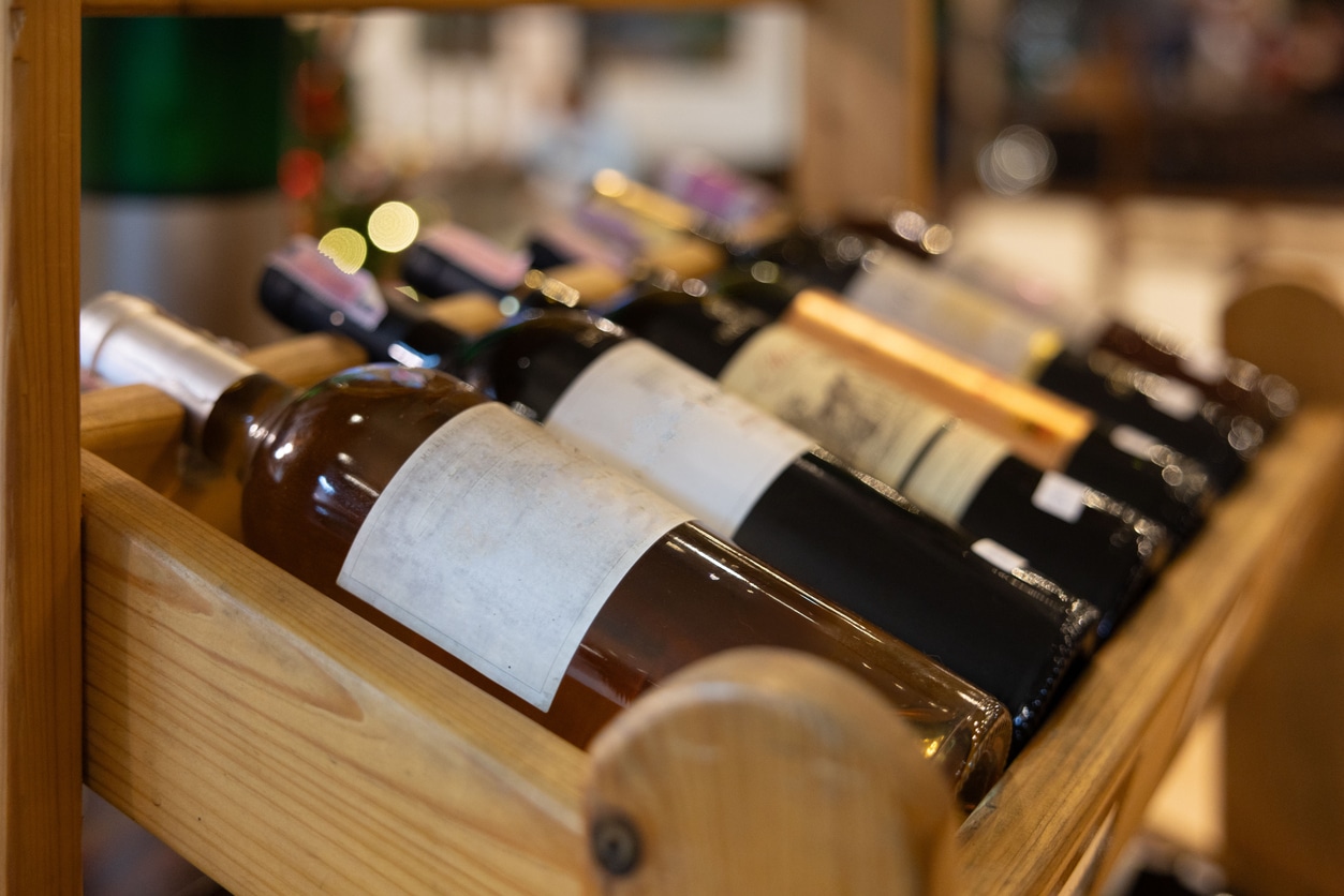 A wooden wine rack with a variety of bottles of wine, proper wine storage
