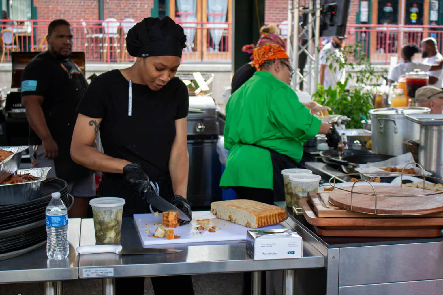 Chef Ke cutting bread and volunteers at the 2025 Juneteenth Farm to Table Dinner